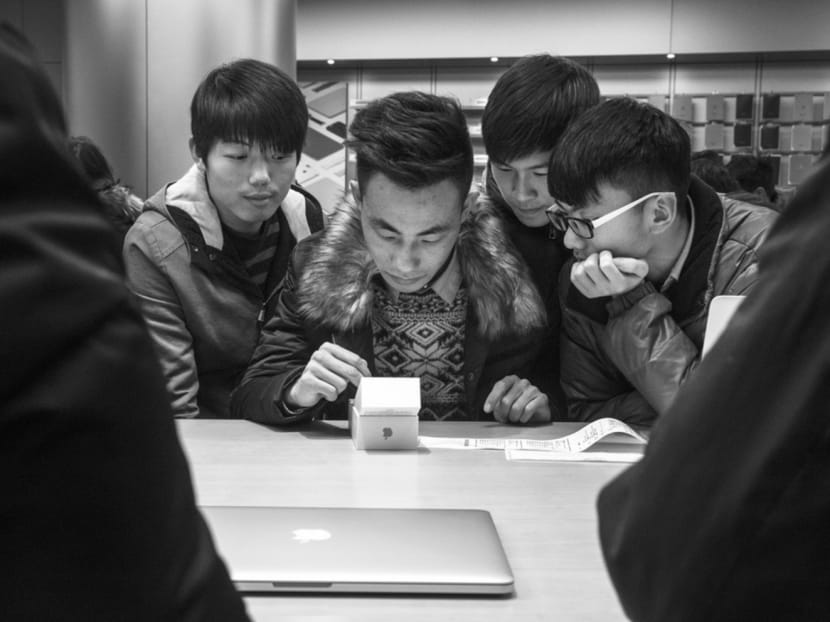 A man setting up his new iPhone 6s as friends look on at an Apple store in Beijing last year. Chinese manufacturers have begun selling phones with similar specs to recent iPhones — Apple is one of the most respected brands in China — but for several hundred dollars less. Photo: The New York Times