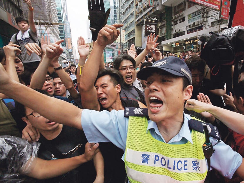 A police officer tries to hold back pro-democracy student protesters during a clash local residents in Mong Kok, Hong Kong, Saturday, Oct. 4, 2014. Friction between pro-democracy protesters and opponents of their weeklong occupation of major Hong Kong streets persisted Saturday as police denied they had any connection to criminal gangs suspected of inciting attacks on largely peaceful demonstrators. (AP Photo/Wally Santana)