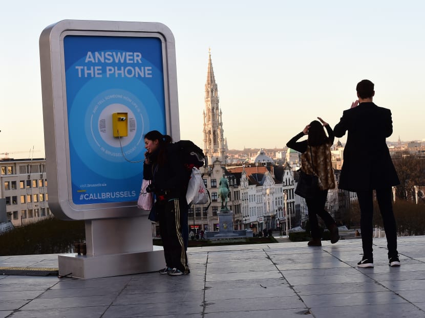 A woman answers a phone, a call box to which internet surfers from around the world can make a call to and randomnly get news from passers-by about the safety of life in Brussels, on Jan 8, 2016. Photo: AFP
