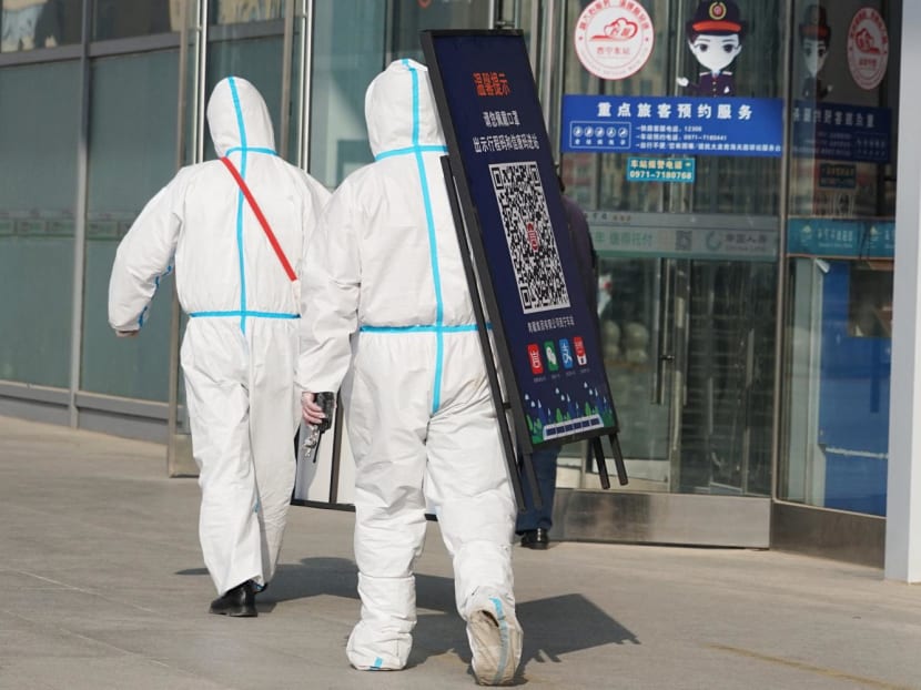 Staff members removing posters for a Covid-19 health code used upon entering the railway station in Xining in China's northwestern Qinghai province on Dec 8, 2022.
