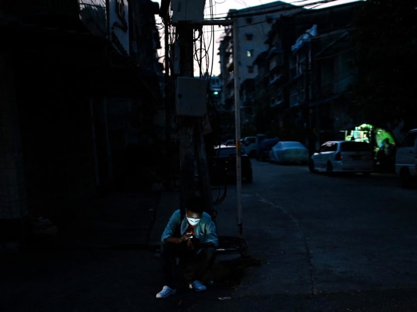 A man uses his mobile phone on a street during a power outage in Yangon on March 3, 2022.