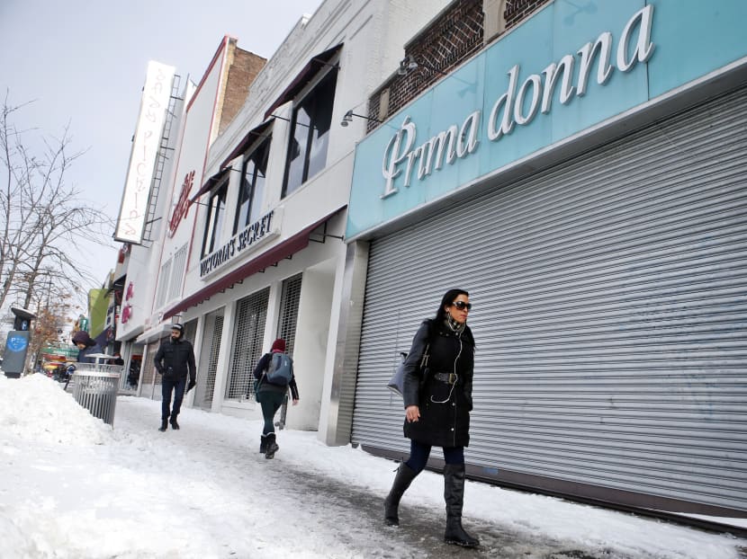 Pedestrians walk past closed businesses along Steinway Street, normally a busy commercial area, following a winter storm, Jan 27, 2015, in the Queens borough of New York. Photo: AP