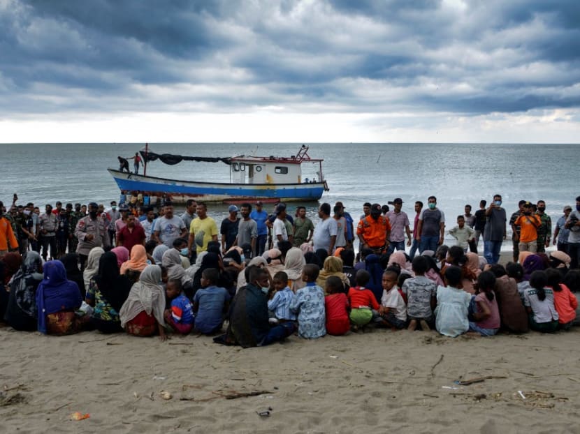 In this file photo taken on June 25, 2020, Rohingya migrants sit by the beach after their boat landed on the shores of Lancok village, in Indonesia's North Aceh Regency.
