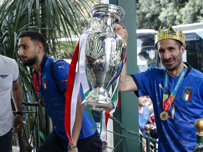 This photo obtained from Italian news agency Ansa shows Italy's captain Giorgio Chiellini (right) carrying the trophy next to goalkeeper Gianluigi Donnarumma (left) as Italy's football team arrive on July 12, 2021 at Parco dei Principi hotel in Rome, after Italy won the Uefa Euro 2020 final football match between Italy and England.