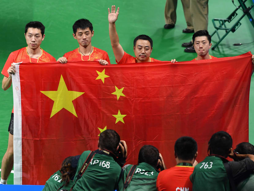 (L-R) China's Xu Xin, Zhang Jike, coach Liu Guoliang, and Ma Long pictured after their men's team gold medal victory at the 2016 Olympic Games in Rio de Janeiro on August 17, 2016. Luis Acosta / AFP