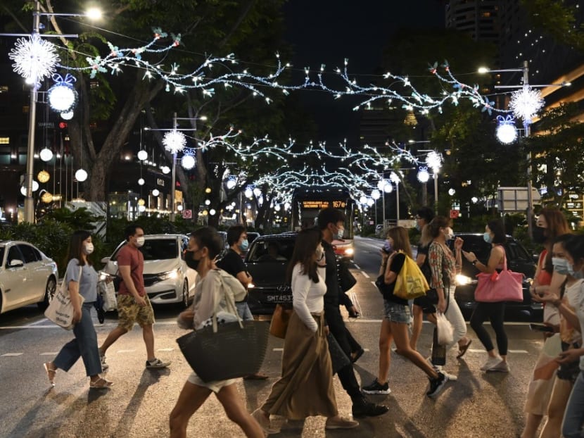 Pedestrians cross a street decorated with Christmas lights in the Orchard Road shopping district in Singapore on Dec 8, 2020.