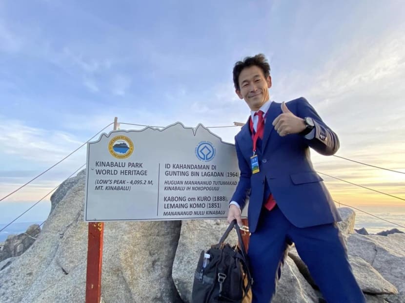 Mr Nobutaka Sada posing in front of a sign at the summit of Mount Kinabalu in Sabah, Malaysia.
