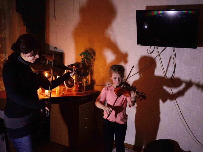 Maryna Bondas (left) and Mariyka Savkevich play violins during a concert in the flat of Savkevich family in Avdiivka. Photo: AFP