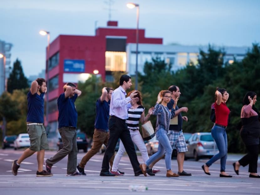 People evacuated from the OEZ shopping mall following a shooting walk with their hands raised in Munich on July 22, 2016. Photo: AFP