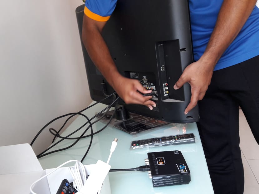 A man demonstrates the installation of a set-top box and an indoor antenna provided by the IMDA.