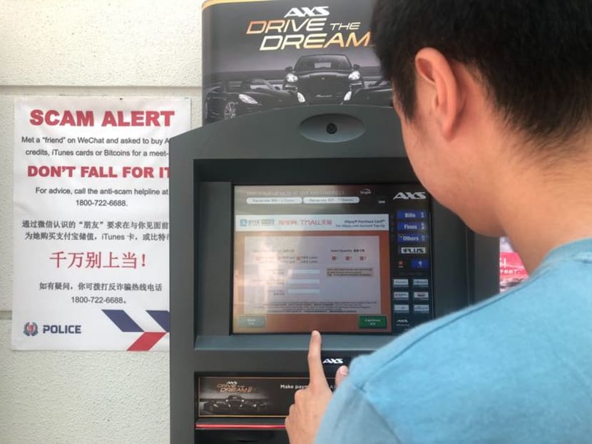Mr Wong, who almost fell victim to an elaborate "credit-for-sex" scam, standing at the Sembawang AXS machine where he was approached by police who guessed his plight. Scam warnings are posted next to the machine.