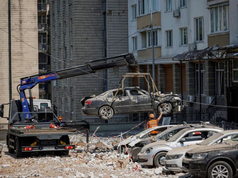 Employees of city services remove destroyed cars from the parking next to an apartment building heavily damaged during a massive Russian drone strike, amid Russia's attack on Ukraine, in Kyiv, Ukraine May 30, 2023. REUTERS/Alina Smutko     