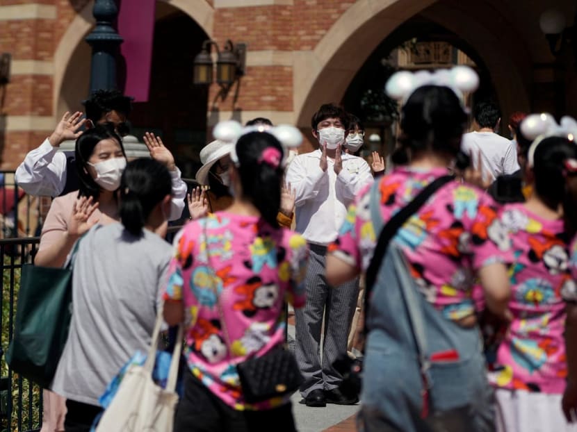 Staff members wearing face masks welcome visitors at the Shanghai Disney Resort, as the Shanghai Disneyland theme park reopens after being shut due to the Covid-19 outbreak, in Shanghai, China on June 30, 2022.