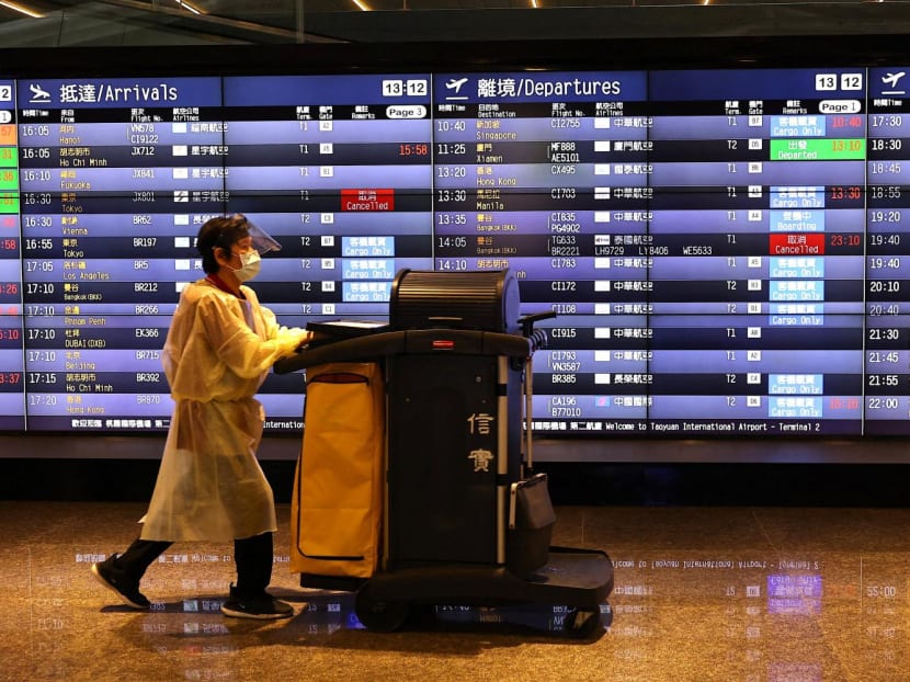 An airport staff member walks past a board showing departure statuses at Taoyuan International Airport in Taoyuan City, Taiwan on Aug 4, 2022.