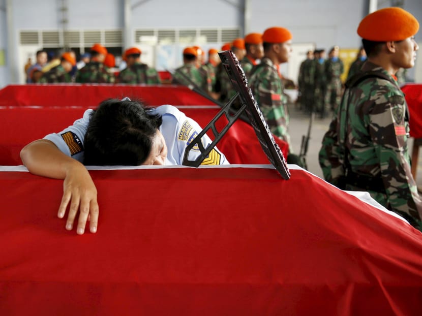 Swet Eka, an Indonesian soldier, mourns on the coffin of her husband (also a soldier), one of the victims in an Indonesian military C-130 Hercules transport plane that crashed into a residential area, inside military airbase in Medan, Indonesia North Sumatra province July 1, 2015. Photo: Reuters