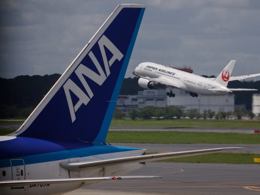 A Japan Airlines passenger plane takes off past another from All Nippon Airways at Tokyo's Narita International Airport in Narita, Chiba Prefecture on July 18, 2021.