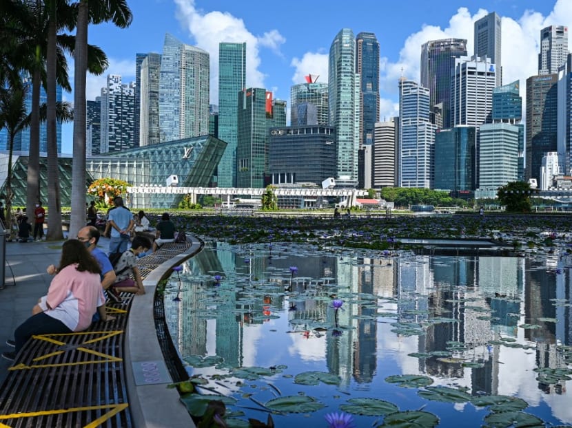 People sitting next to a pond with a view of Singapore's business district.