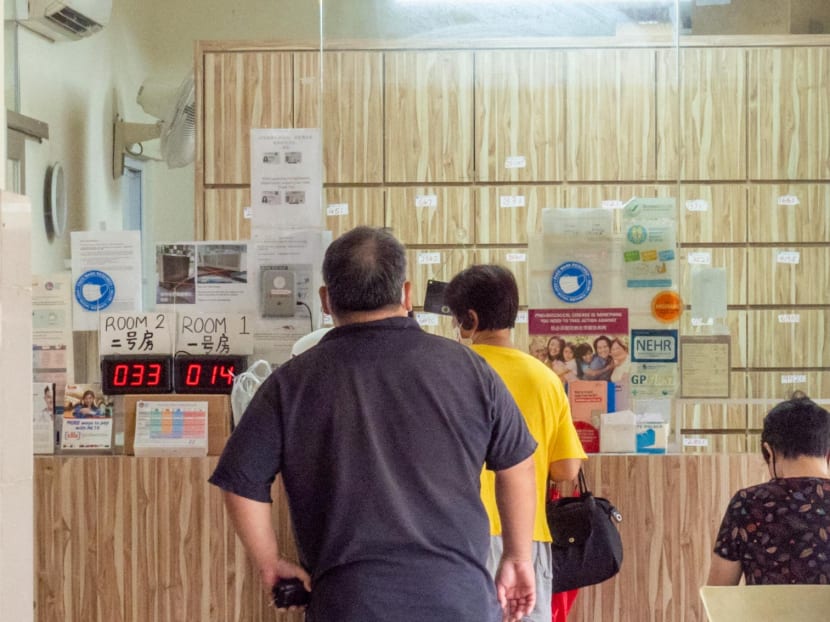 People queueing at the reception counter of a private clinic in a housing estate.