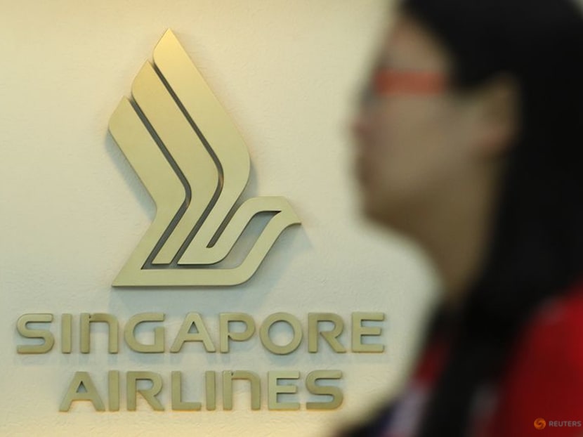 A woman walks past a Singapore Airlines (SIA) logo at a ticketing booth at Changi airport in Singapore.