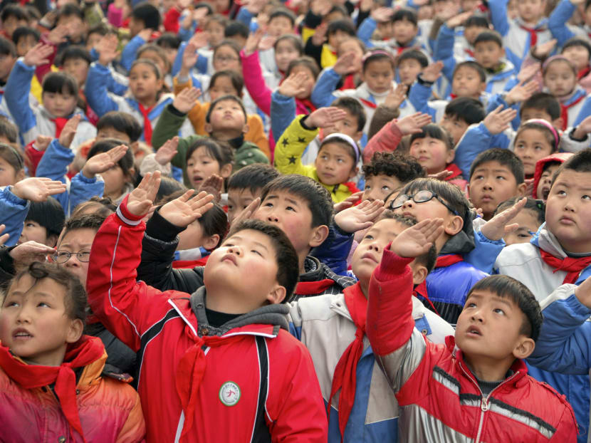 Children salute during a flag-raising ceremony on the first day of their new semester at a primary school in Bozhou, Anhui province March 2, 2015. Photo: Reuters