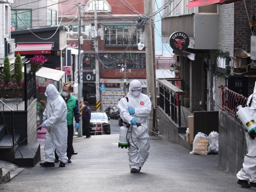 Health workers spray disinfectant on a street in the Itaewon district of Seoul on May 12, 2020.