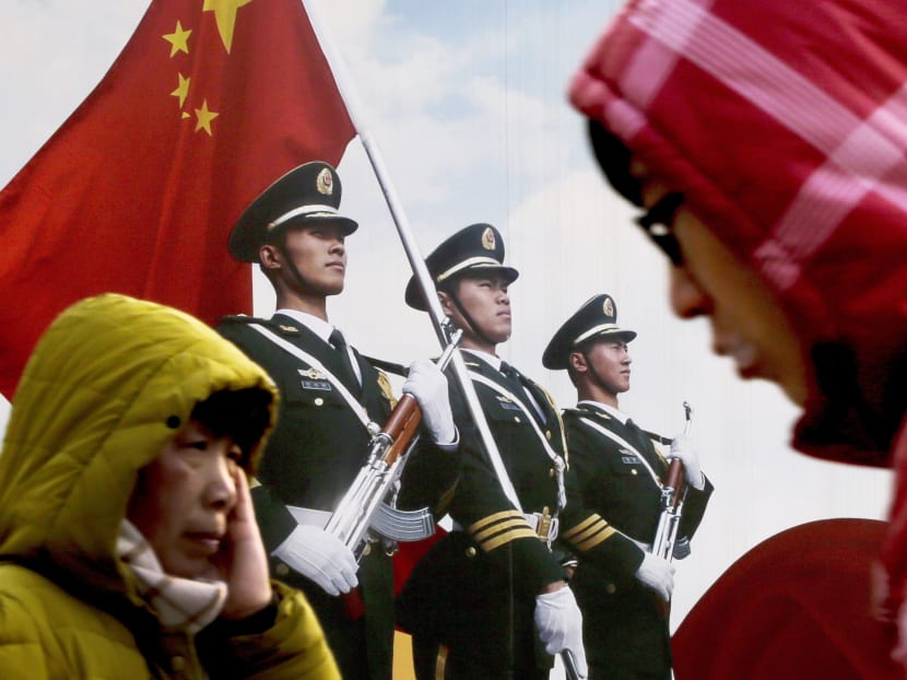 People walking past a poster of Chinese People’s Liberation Army soldiers on display in Beijing. Photo: AP