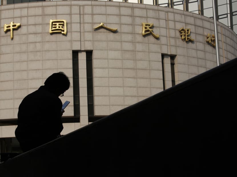 A man sits in front of the headquarters of the People's Bank of China, the central bank, in Beijing Oct 17, 2013. Photo: Reuters