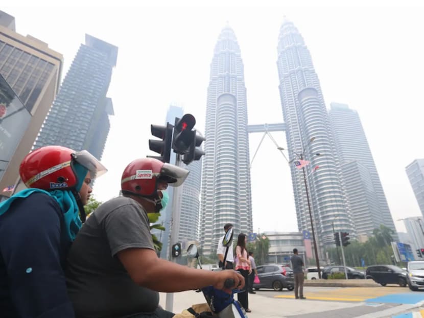 A motorist wears a mask as he travels past the Petronas Twin Towers shrouded in haze in Kuala Lumpur September 12, 2019.
