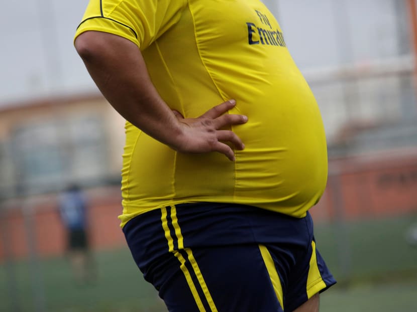An obese man watching a football match. A federal lawmaker from the ruling Barisan Nasional (BN) coalition claims Malaysia is fortunate as its people could afford to overeat. Photo: Reuters