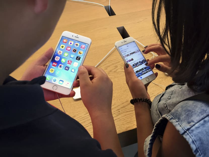 Customers try out Apple iPhone 6S models on display at an Apple Store in Beijing, Saturday, June 18, 2016. Photo: AP